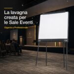 Il Meeting nel Centro Direzionale: Allestimento Sala Conferenze d'Élite 3 Lavagna a fogli mobili professionale KING posizionata all'interno di una sala eventi con pubblico. Testo nell'immagine: La lavagna creata per le Sale Eventi. Gigante e Professionale